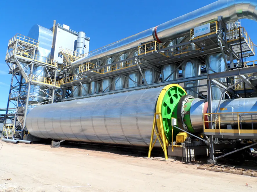 Large rotary dryer drum with a green drive ring, in front of a bank of gas cleaning units linked by ducts