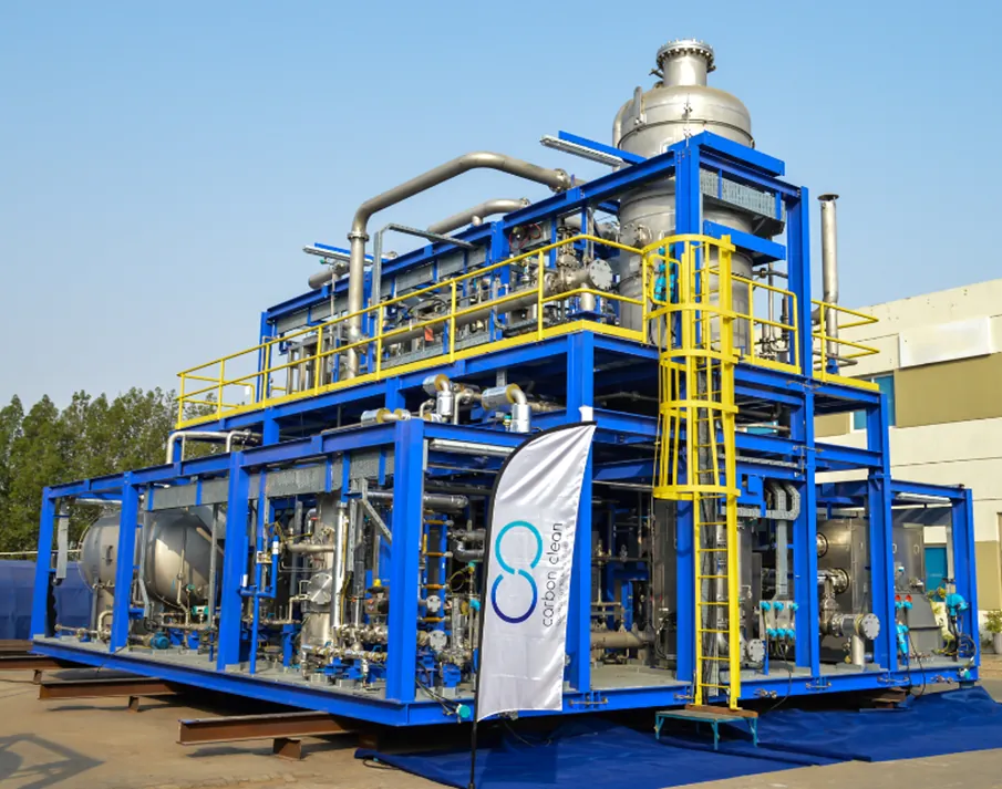 Fotografía de una unidad modular de captura con aminas de Carbon Clean sobre bastidor azul, con columna, tuberías y escaleras de acceso amarillas